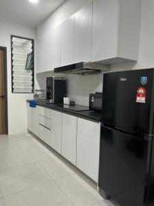 古晋Armadale Residence-Gala City的厨房配有黑冰箱和白色橱柜。