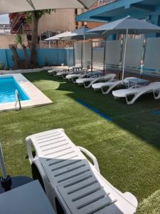 多列毛利诺斯Apartamentos El Velero的游泳池旁的一排躺椅和遮阳伞