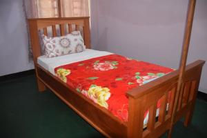 莫希Kili View Lodge的一张带红色毯子和枕头的木床