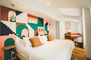 盖塔里布里克特尼亚酒店的卧室配有白色床和色彩缤纷的墙壁