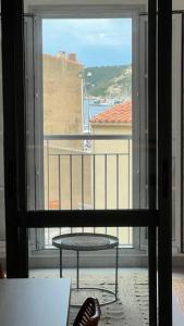博尼法乔D24- T3-Les Hauts du Port-parking-clim-wifi-50m du port的阳台设有桌子和窗户,享有风景。