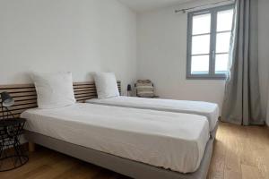 博尼法乔D24- T3-Les Hauts du Port-parking-clim-wifi-50m du port的白色客房的两张床,设有窗户