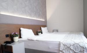 伊斯坦布尔尼康亚港口套房及酒店的一间卧室配有一张白色大床,床上有鲜花