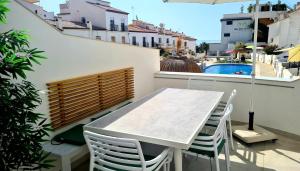 内尔哈Casa-Mar Nerja的一个带游泳池的阳台,配有一张白色的桌子和椅子