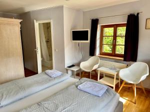 福森Pension Steakhaus Füssen的一间卧室配有两张床、一台电视和椅子