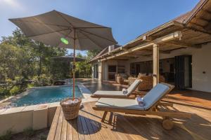 侯斯普瑞特Ukanyi Luxury Villa的游泳池旁的甲板配有两把椅子和一把遮阳伞