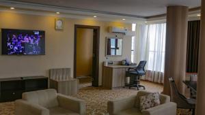 亚的斯亚贝巴Holiday Hotel Addis Ababa的一间带两把椅子的客厅和一间带电视的客厅