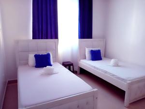 姆特瓦帕Homestay Luxurious apartments with swimming pool的客房内的两张白色床和蓝色枕头