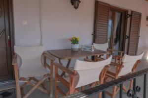卡兰巴卡Villa Nefeli的阳台上的木桌和椅子