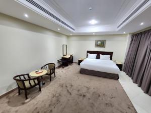 达曼S Maskan Hotel的酒店客房带一张床、一张桌子和椅子