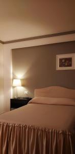 兰恰诺Hotel Excelsior的一间卧室配有一张床和一张桌子上的台灯