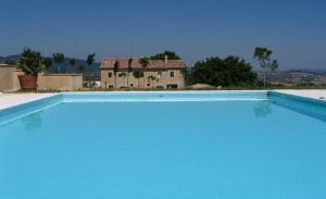 MergoAgriturismo Colle delle Stelle的一座大型蓝色游泳池,后面有一座房子