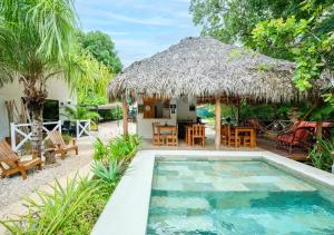塔马林多Antema Lodge Secteur Tamarindo, piscine, yoga, gym, jungle et paix的一座带游泳池和茅草屋顶的别墅