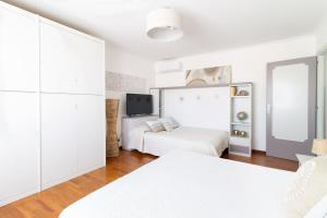 托瓦尼亚Attico Centralissimo Vista Mare的一间白色卧室,配有两张床和电视