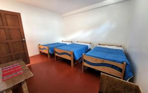 库斯科Peru Hostel Inn Plaza的一间设有两张床、一扇门和一张桌子的房间
