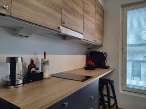坦佩雷Ydinkeskustassa, uusi yksiö+ autohallipaikka的厨房配有木制橱柜和台面
