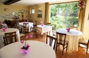 MergoAgriturismo Colle delle Stelle的餐厅配有白色的桌椅和粉红色的鲜花