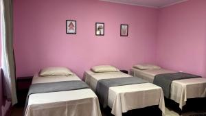 阿莱格雷特Pousada Mercosul的配有粉红色墙壁的客房内的两张床