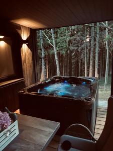 PaplatelėCocodeno-'Virš Ąžuolų' - Forest SPA - FREE jacuzzi的一个带桌子的客房内的按摩浴缸