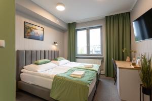 奥古斯图Apartamenty Albatros的酒店客房设有一张床、一张书桌和窗户。