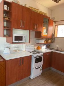 ShimwansaSerene & quiet 2- Bedroom Cottage Statelodge area的厨房配有木制橱柜和白色炉灶烤箱。