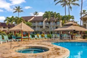 卡帕阿Islander Ocean Resort Condo # 166的一个带椅子和遮阳伞的游泳池的度假酒店