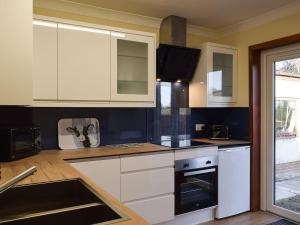 克里夫The Hoolit的厨房配有白色橱柜和炉灶烤箱。