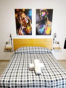 塞维利亚Arc House Plaza的卧室配有一张床铺,墙上挂着两张海报