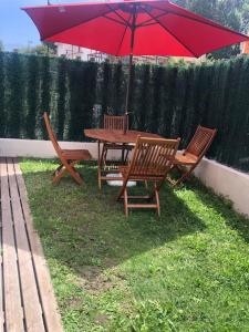 巴罗德亚尼斯El Gurugú, apartamento con jardín en la playa de Barro的野餐桌和带红伞的椅子