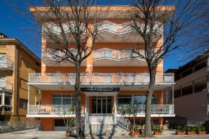 里米尼Hotel Ravello da Lorenzo e Moira的一座橙色的建筑,设有阳台和两棵树
