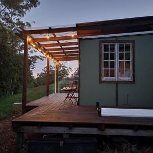 贝林真Bellingen Hideaway Tiny Home- Breathe. Discover. Renew.的房屋的门廊,甲板上配有桌子