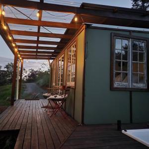 贝林真Bellingen Hideaway Tiny Home- Breathe. Discover. Renew.的房屋设有1个带桌子和窗户的甲板