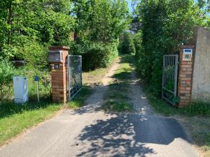 Tornower Waldhäusl, perfekt gelegen 60 km vor Berlin, auf der Schwelle zum Spreewald und nahe Tropical Islands的一条有门和树木的土路