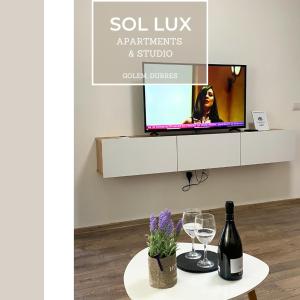 都拉斯SOL Lux Apartments 1st Floor的一张桌子、酒杯和墙上的电视