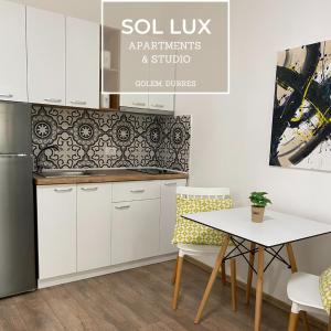 都拉斯SOL Lux Apartments 1st Floor的厨房配有白色橱柜和桌椅