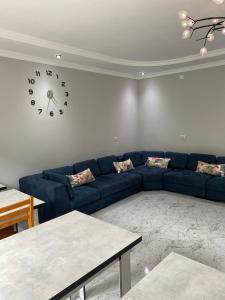 乌雷基Sunrise Ureki的客厅配有蓝色的沙发和墙上的时钟