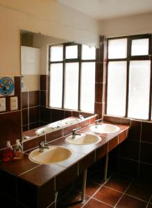 乌尤尼Rummy Hostal的一间带三个盥洗盆和两个窗户的浴室