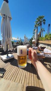安塔利亚Flat For Rent Near The Beach, Konyaaltı, Antalya的海滩上桌上拿着一杯啤酒的人