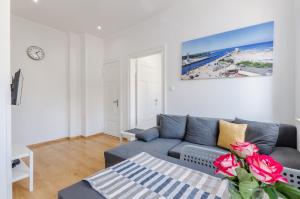 乌斯特卡Pod Muralem - Apartamenty Little Heaven的客厅配有蓝色长沙发及玫瑰花瓶