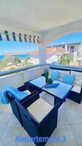 维尔Croadriatic Apartments的阳台配有蓝色的桌椅,享有海景。