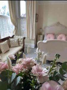 洛斯托夫特月桂树别墅酒店的客厅配有粉红色的鲜花和沙发