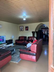 弗里敦Yogi Home Stay Near Freetown Airport的坐在客厅沙发上的人