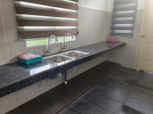 Kampong BelukarHOMESTAY MYROKMA的带两个水槽的厨房台面和窗户