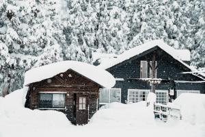 妙高Mountain Hut Myoko的被雪覆盖的小屋,有树