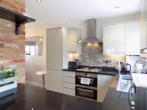 埃姆斯伯里Double Award Winning, Stunning 1700's Grd 2 listed cottage near Stonehenge - Elegantly Refurbished Throughout的厨房配有白色橱柜和炉灶烤箱。