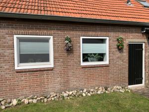 HoogersmildeOnze boerderij的砖屋,设有两扇窗户和一扇门
