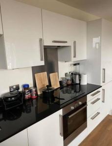 伦敦1 bedroom apartment的厨房配有白色橱柜和黑色台面