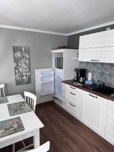 洛布Ferienhaus/Bungalow Lobbe - 60qm的厨房配有白色橱柜、桌子和柜台。