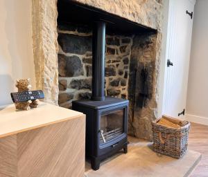SilsdenSwartha Cottages的客厅设有石墙,配有炉灶