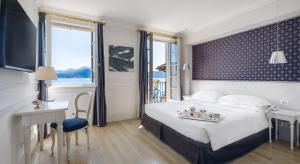 卡尼洛瑞维拉Hotel Cannero的酒店客房设有一张床、一张书桌和窗户。